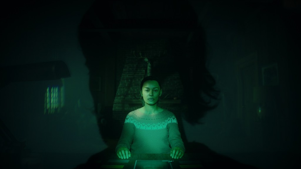 Alan Wake 2: Saga Anderson sat at a desk and bathed in a green glow.